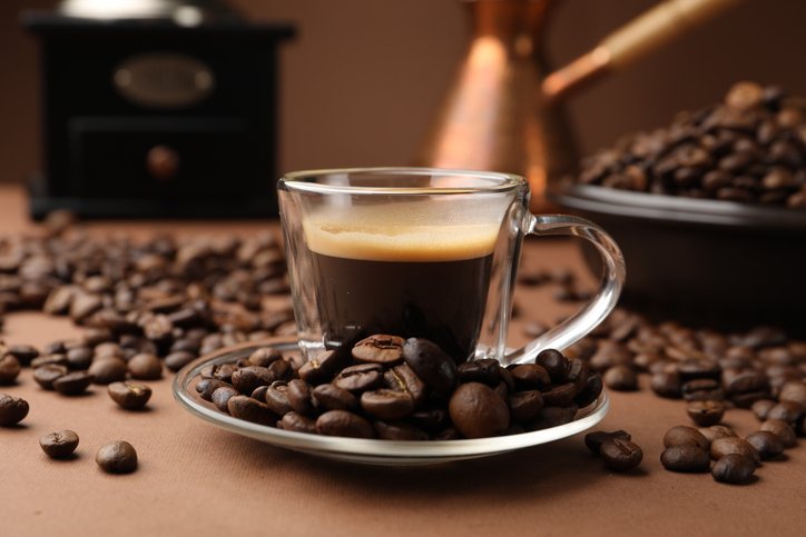 El café sale amargo: espresso oscuro en vaso rodeado de granos
