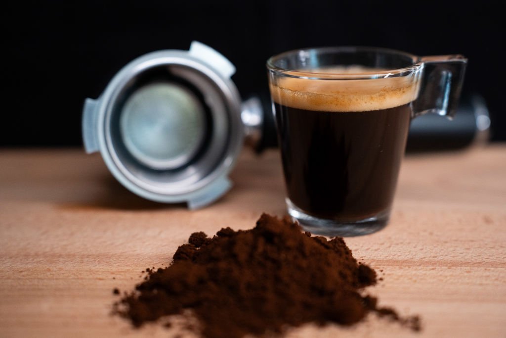 Portafiltros limpio junto a un espresso, tras usar descalcificadores